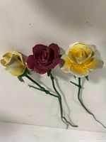 Front view of three porcelain roses showing petal colors and stems