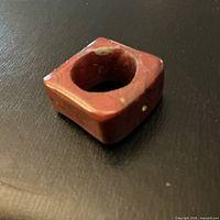 Square hardstone ring angled view showing reddish-brown color and circular opening
