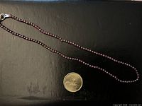 Full view of garnet bead necklace beside coin for scale