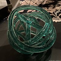 Overall view of teal glass knot sculpture showing intertwined loops