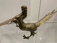Both cast metal pheasant figures side by side showing relative size and detail