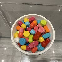 Top view of white bowl filled with colourful pill shapes