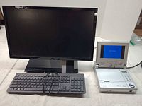 Front view of all items: Acer monitor, portable DVD player powered on, keyboard and VGA cable