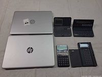 Two closed HP laptops with four calculators/organizers displayed