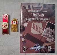Front cover of NHL 1947-48 Press & Radio Guide beside both enamel pins