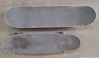 Top view of both skateboards showing black grip tape and size difference