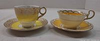 Side view of both teacups on their saucers showing colour and gilt detail