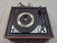 Top view of Dual 1215 turntable showing platter, tonearm, wood plinth, RCA cables