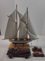 Group view of sailboat with three wooden toy cars
