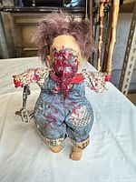 Front view of doll showing outfit, red painted face, attached stand