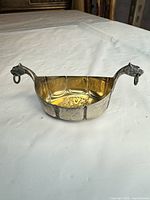 Oblique view showing overall shape, gilt interior, animal head handles with rings