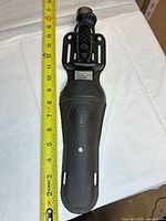 Knife in sheath beside tape measure showing overall length