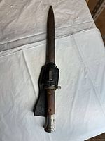 Full view of bayonet seated in leather scabbard