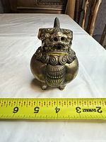 Front view of brass Foo Dog incense burner with ruler showing size