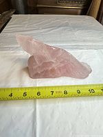 Profile of rose quartz alligator beside tape measure showing length