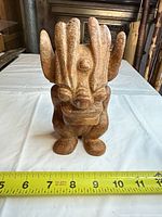 Front view of brown cast stone gargoyle statue beside tape measure