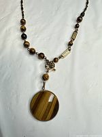 Close view of tiger's eye pendant, beads, toggle clasp and bar links