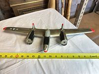 Top view showing full wingspan with measuring tape, silver-green finish, insignia, red tips