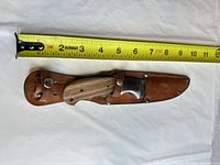 Knife in sheath with tape measure showing length