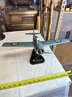 Oblique front view of model airplane on stand with measuring tape for scale reference