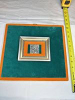 Full view showing framed plaque with tape measure for scale