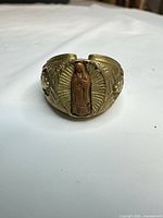 Front view showing raised religious figure and radiating rays on ring