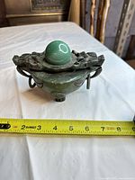Top view of censer showing orb finial, lid carving, tape measure indicating width