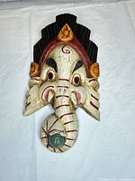 Front view of carved wooden Ganesha mask showing paint colors and features