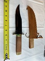 Knife beside measuring tape showing approx 13 in overall with sheath alongside
