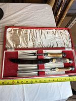 Open presentation case showing carving knife, fork and steel with tape measure for scale