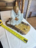 Front view of celadon scholar figurine with tape measure showing length