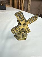 Front view of small brass windmill showing blades, tower and base