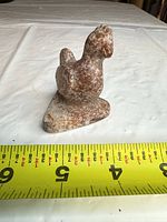 front angled view of the small stone bird figurine with measuring tape showing size