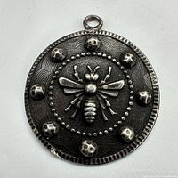 Front view of sterling silver pendant showing bee motif and dotted border
