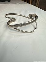 Oblique front view of sterling silver cuff showing hammered band and crossover wires