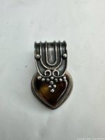 Front view showing heart-shaped tiger's eye cabochon in sterling setting with decorative bail
