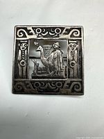 Front view of square sterling silver brooch with Andean figure and llama scene