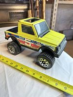 Full view of yellow Tonka race truck showing tape measure for scale