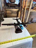 Front three-quarter view of model on stand, tape measure showing scale