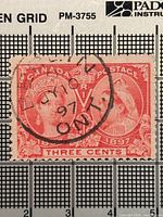 Front of red 3-cent Diamond Jubilee stamp with cancellation mark, grid background for scale