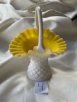 Full view of Kanawha milk glass basket showing white exterior, yellow interior, handle, ruffled rim