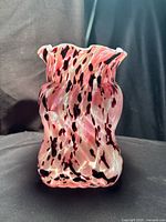 Front view of pink, white, oxblood spatter cased glass vase