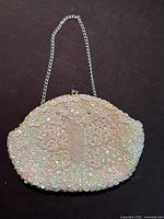 Front view of Du Val white beaded clutch with silver chain