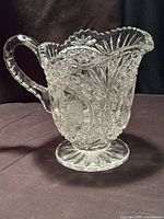 Full view of crystal pitcher showing shape, handle, scalloped rim