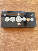 Front view of acrylic block with six coins, two pins, posts visible