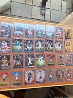Full grid view of 28 sleeved football cards on tabletop