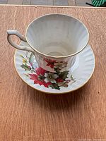 Teacup on saucer showing poinsettia pattern and gold rim