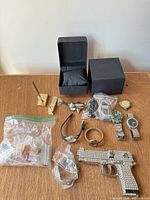 Group shot of all items: watches, rhinestone gun, bags, boxes, tie clips