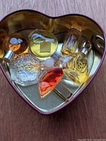 Group view of all six miniature perfume bottles inside heart-shaped tin