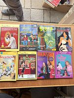 All eight paperback books laid out on table top